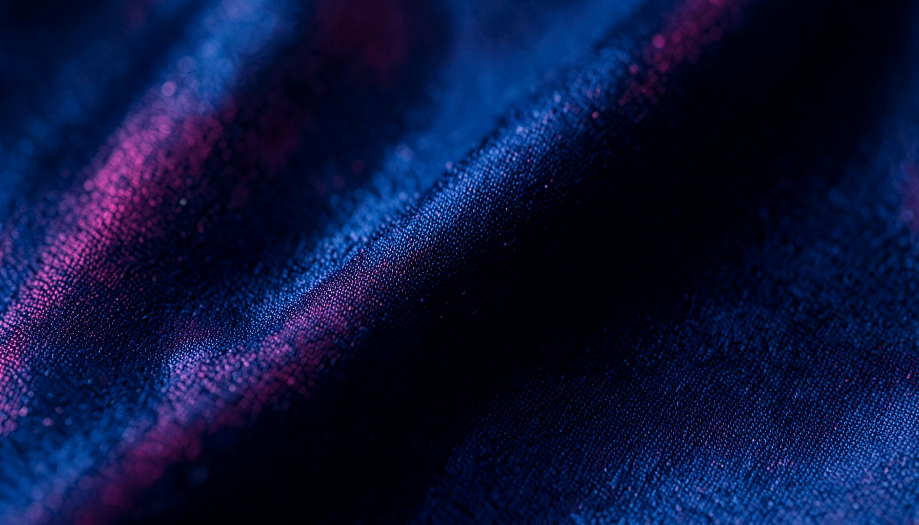 Extreme close-up of midnight blue satin with soft magenta iridescence