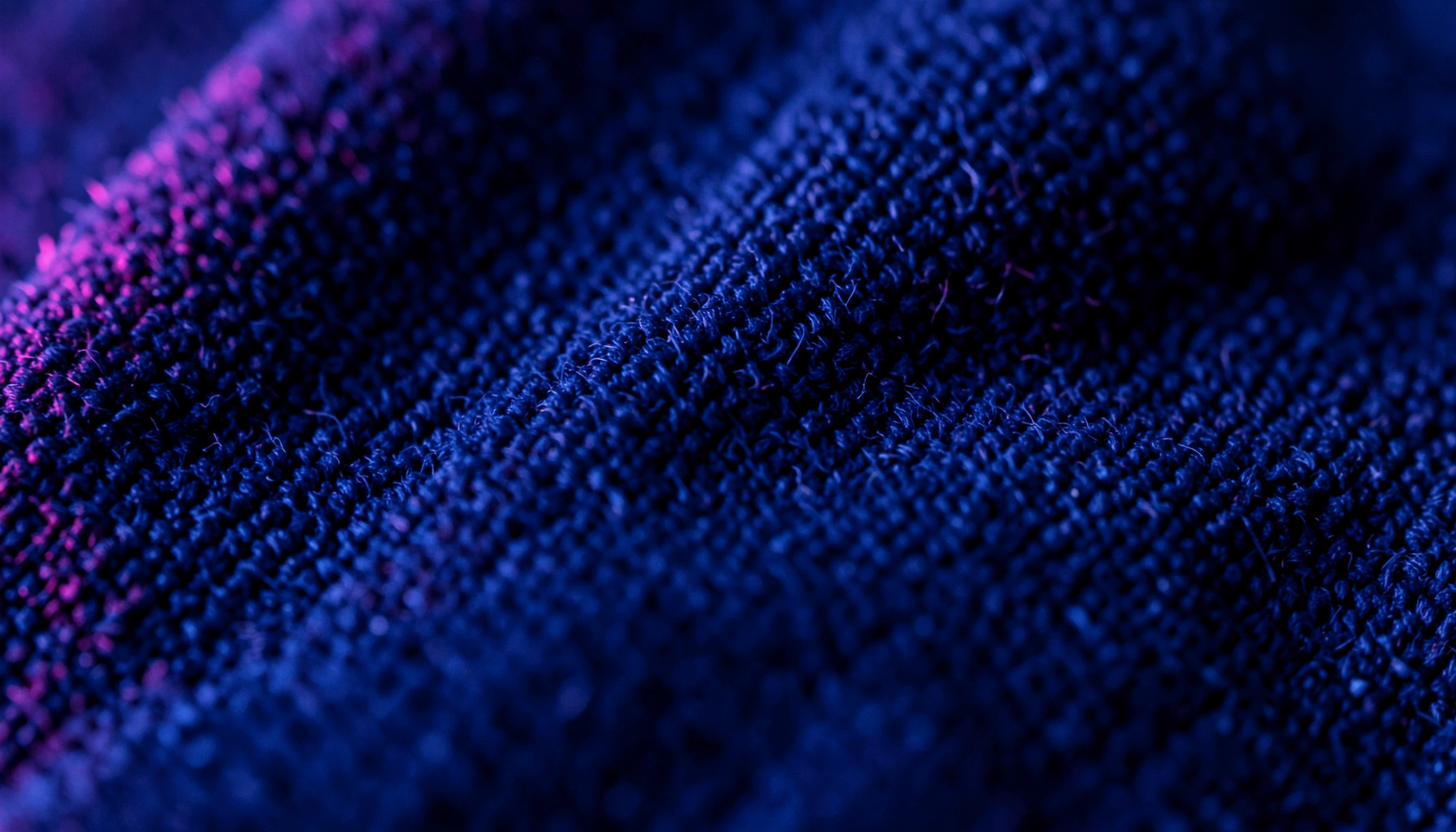 Extreme close-up of midnight blue microfiber texture with soft magenta edge lighting